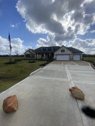 Model Home A beautiful stone house with a spacious driveway and flagpole in Barton Place by First America Homes (Cleveland, TX).