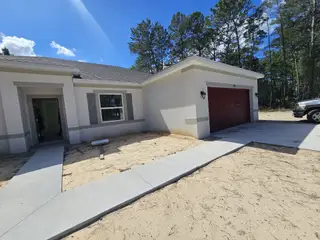 A charming white-brick home with a red garage in Citrus Springs by Holiday Builders (Citrus Springs, FL).