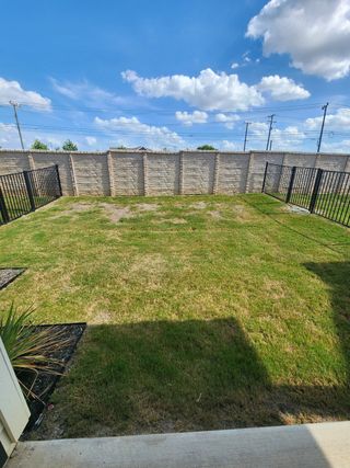 Model Home A spacious backyard with a stone fence and lush grass, perfect for outdoor activities.