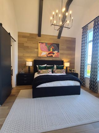 A cozy bedroom with wood accent wall, stylish chandelier, and chic decor, featuring a plush bed and modern artwork.