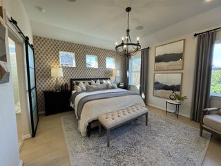A serene and stylish primary bedroom with a tufted accent wall, a grand chandelier, and a calming neutral color palette.