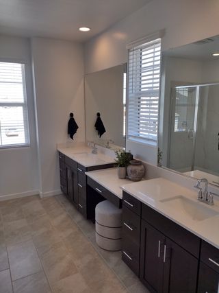 Model Home A sleek bathroom featuring dual dark wood vanities, elegant lighting, and modern tile flooring.