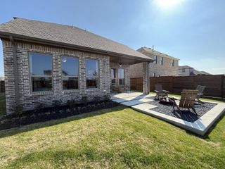 A serene backyard retreat with a fire pit, lush lawn, and covered patio in Solterra by Chesmar Homes (Mesquite, TX).