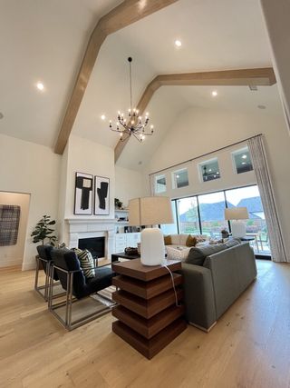 Model Home A spacious living room with a vaulted ceiling, elegant chandelier, and modern fireplace, offering a cozy and stylish ambiance.