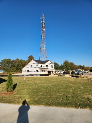 Street view A partially constructed home beside a towering radio mast in Grove At Gin Branch by Mattamy Homes (Wendell, NC).