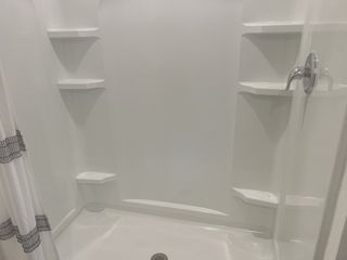 A sleek shower with built-in shelves, chrome fixtures, and a simple white curtain for a clean, modern look.