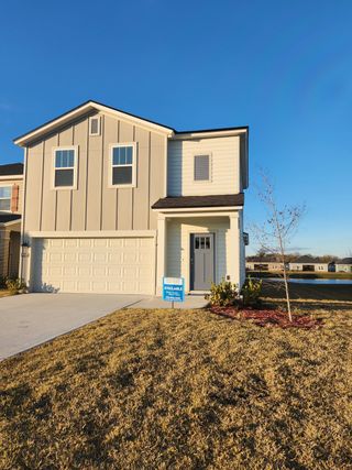 A modern beige two-story home with a manicured lawn in Saddle Oaks by Breeze Homes (Jacksonville, FL).