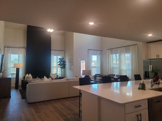 Model Home An open living space with a sleek kitchen, cozy seating, large windows, and modern decor.