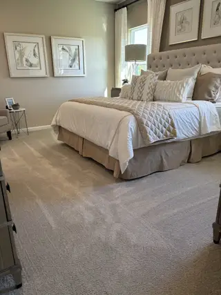 Model Home A cozy bedroom with a tufted headboard, elegant artwork, and soft lighting creating a tranquil ambiance.