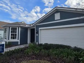 Street view A charming blue home with white trim and lush landscaping in Summer Bay at Grand Oaks by Pulte Homes (St. Augustine, FL).