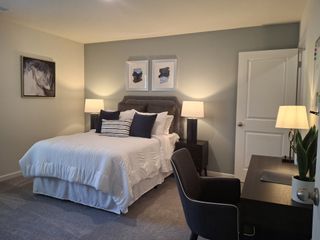 A cozy bedroom with a plush bed, modern art, elegant lighting, and a sleek desk setup for work or study.