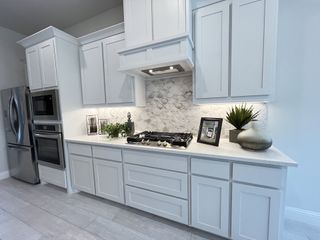 Sleek white kitchen with stainless steel appliances, a gas stove, and stylish decor, creating a fresh and clean look.