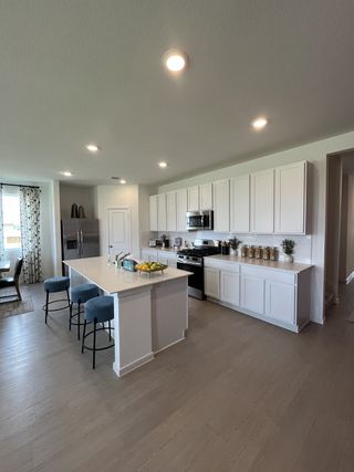 A modern kitchen featuring white cabinetry, a large island with seating, and sleek appliances, offering a spacious layout.