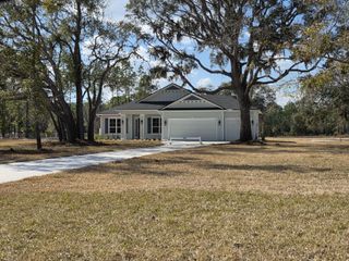 Street view A charming single-story home with a spacious yard and mature trees in Edwards Creek Estates by SEDA New Homes (Jacksonville, FL).