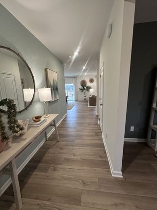 A chic hallway featuring wood floors, elegant decor, and modern lighting, leading to a bright living area.
