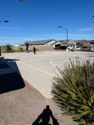 A sunny basketball court in McClellan Ranch - Reserve Series by Meritage Homes, Laveen, AZ with nearby greenery and homes.