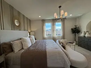 A cozy bedroom with a plush bed, chic chandelier, and elegant decor. Soft lighting and neutral tones create a relaxing ambiance.