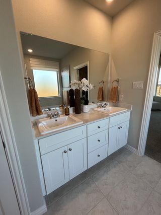A modern bathroom with a sleek vanity, tiled shower, and warm-toned accents in Solterra by Chesmar Homes (Mesquite, TX).