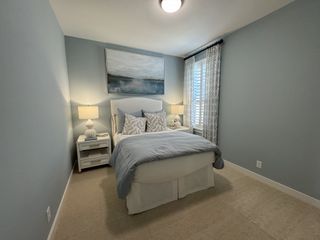 Model Home A cozy bedroom featuring soft blue walls, a plush bed, modern artwork, and elegant patterned curtains.