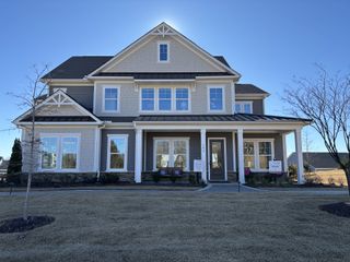 Street view A charming grey home with gable details and a spacious porch in McLean South Shore by Tri Pointe Homes (Belmont, NC).
