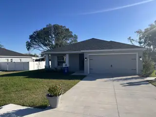 A modern gray home with a spacious driveway in Silver Springs Shores by Highland Homes of Florida (Ocala, FL).
