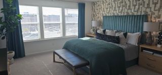 A spacious bedroom with a plush green bed, patterned wallpaper, and natural light from large windows in Bethlehem, GA.
