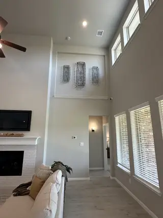 Model Home A bright, open living room with high ceilings, modern wall art, a cozy fireplace, and abundant natural light from large windows.