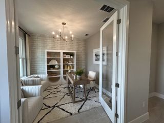 A cozy home office with plush armchairs, a modern chandelier, and a geometric rug, creating a welcoming atmosphere.