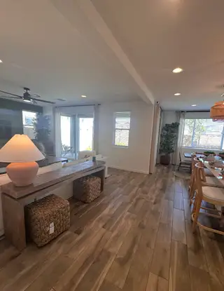 Model Home An inviting living room with wood-style flooring, cozy seating, and abundant natural light from large windows and doors.