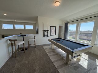 Model Home A bright game room featuring a sleek pool table, cozy seating nook, and large sunny windows creating a perfect leisure space.