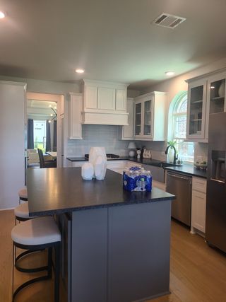 A modern kitchen with sleek black countertops, white cabinetry, and stainless steel appliances.