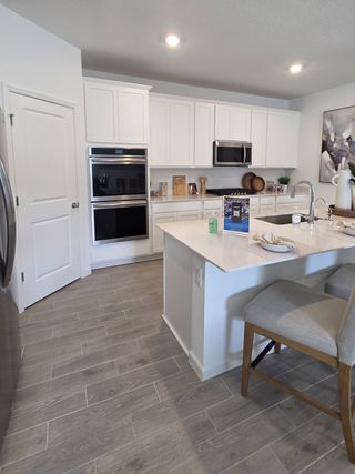 Model Home A modern kitchen with sleek white cabinets, stainless steel appliances, and a spacious island with seating.