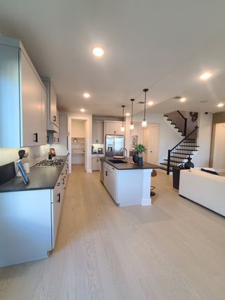 A modern kitchen featuring sleek cabinetry, pendant lighting, and an inviting open layout with a stylish staircase nearby.