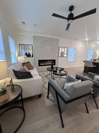 Model Home A cozy living room with a sleek fireplace, modern ceiling fan, and stylish seating arrangement.