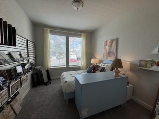 A uniquely designed bedroom that doubles as a creative workspace, featuring a variety of material samples on display. The large window brings in natural light, making it a functional and bright space.
