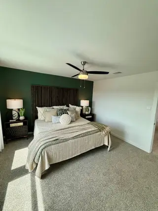 A cozy bedroom with a deep green accent wall, plush bedding, and stylish lamps, creating a serene retreat.