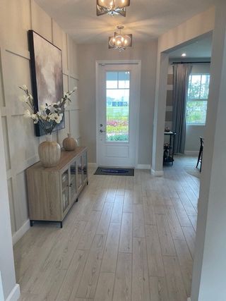 A bright, inviting foyer with wood flooring and elegant decor, leading to a spacious, light-filled room.