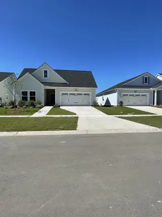 A charming white home with a lush yard in Horizons at Carnes Crossroads | 55+: Legends Collection by Lennar (Summerville, SC).