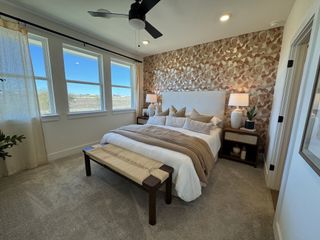 A cozy bedroom with a patterned accent wall, large windows, neutral decor, and modern lighting.
