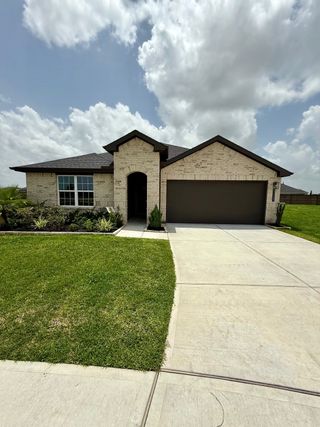A charming brick home with a lush lawn and modern facade in Tamarron by D.R. Horton (Fulshear, TX).