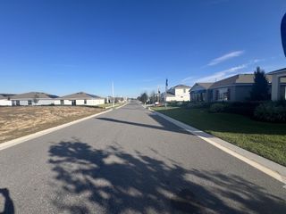 A picturesque neighborhood street lined with modern homes in Cypress Park Estates by D.R. Horton (Haines City, FL).