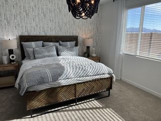 A cozy bedroom with rustic wood accent wall, elegant bedding, and natural light filtering through blinds.