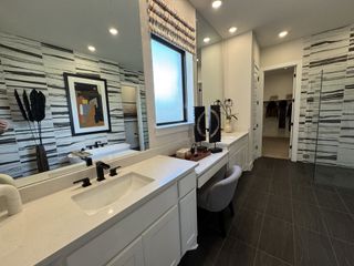 A sleek and modern bathroom featuring a dual vanity, bold black-and-white tile accents, and a walk-in closet.