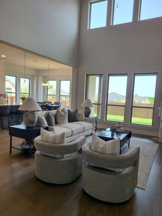 Model Home A spacious living area with high ceilings, cozy seating, and ample natural light through large windows.