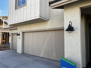 Street view Beige modern garage with farmhouse-style paneling and black metal lamps. A clean and minimalist aesthetic.