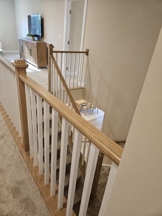 A cozy upstairs hallway with soft carpeting, wooden handrails, and modern decor, leading to a furnished living area.