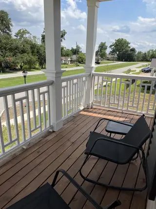 A serene porch with wooden flooring and cozy seating, perfect for relaxation.