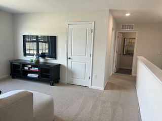 A cozy living area with soft carpet, modern TV setup, and hall access, offering a comfortable and stylish ambiance.