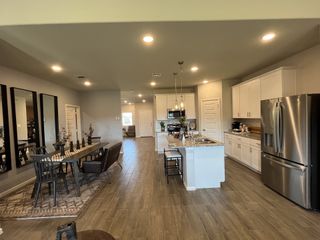 A modern kitchen and dining area with sleek appliances, wood flooring, and contemporary lighting.