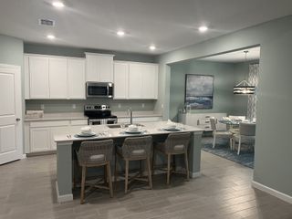 A modern kitchen with sleek white cabinets, a large island with seating, and an elegant dining area in soft blue tones.